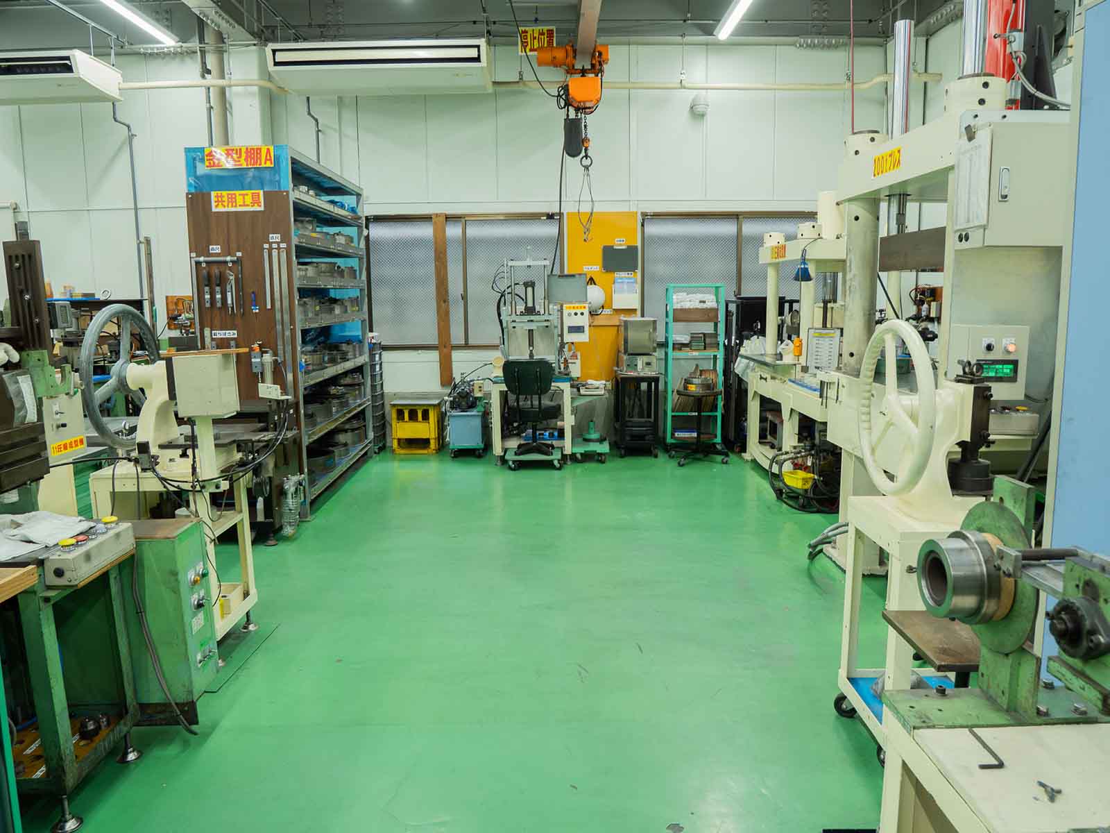 床が明るい緑色に塗装され、棚や機械が整然と配置された、見通しの良い現在の製造現場。