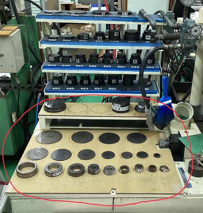 3S活動での改善前、段ボールの上に無造作に置かれているプレス機の治具。