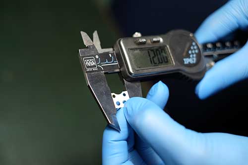 デジタルノギスで1.2mmの微細加工部品を測定する品質管理の様子