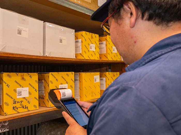 QRコードを『ピッ』とするだけで在庫登録。パソコン入力の手間を省き、現場で作業の『ついで』に情報の清掃を完結させる様子。
