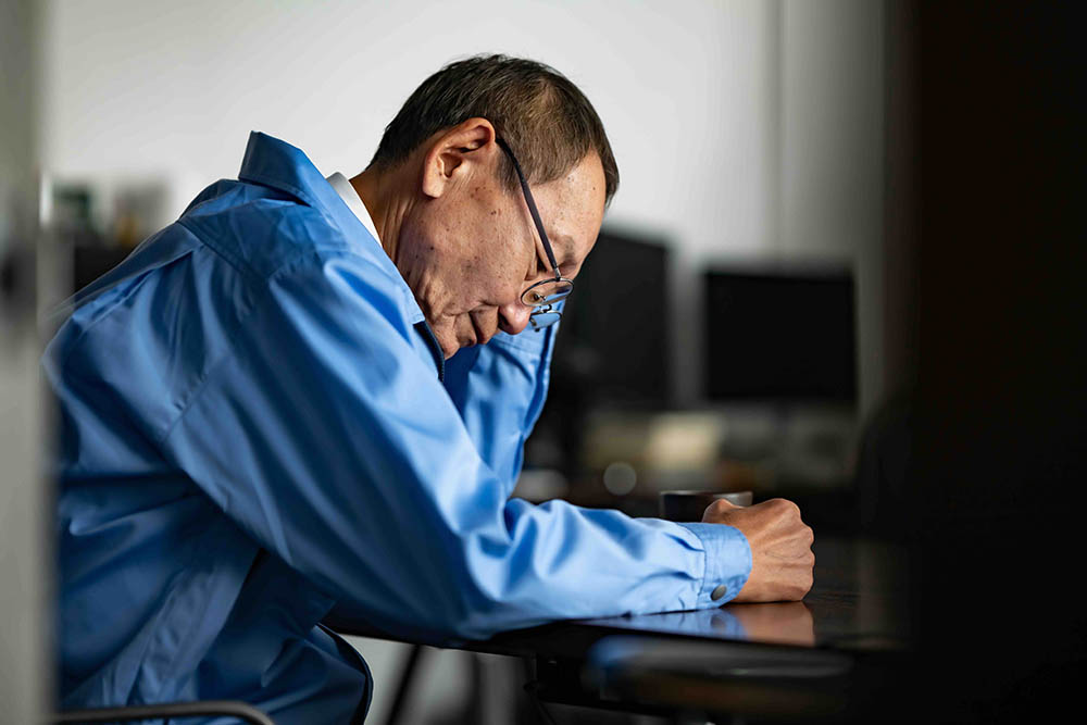 在庫管理の二重手間に悩み、頭を抱える現場のプロ。探しものという付加価値のない時間が、工場の利益とやる気を削っている様子