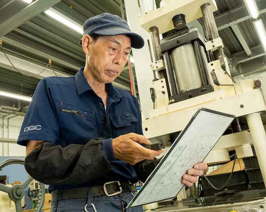 70代のベテラン職人が専用リモコンで実績入力を行う様子。ITが苦手な方でも『ピッ』と直感的に操作でき、現場が主役になる管理を実現します。