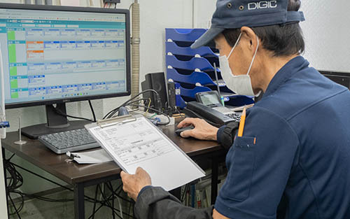 紙の作業指示書と生産管理システムの画面を確認してデータ入力を行うデジックの作業員