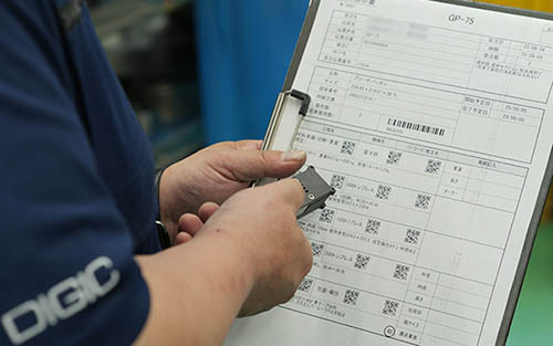 製造現場で作業指示書のQRコードを専用ハンディリモコン「AssistBoardRemocon」で読み取り生産実績を残す様子